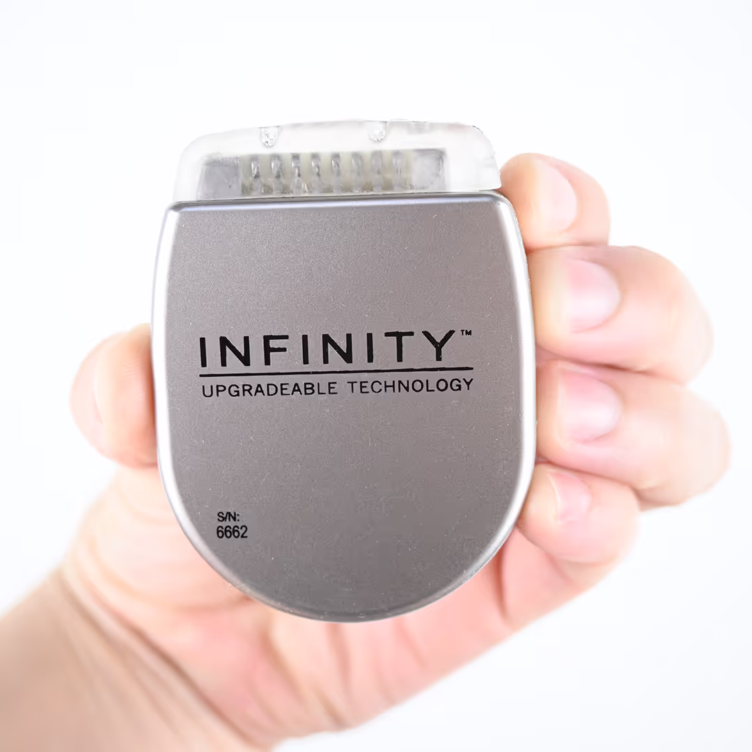 Dispositivo INFINITY™ da Abbott segurado por uma mão. O gerador de pulso implantável é utilizado em terapias de estimulação cerebral profunda para tratamento de Parkinson e tremor essencial.