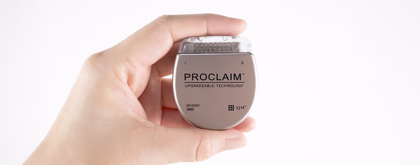 Imagem de um dispositivo Proclaim™ DRG Stimulator da Abbott, segurado por uma mão. O estimulador implantável oferece tecnologia avançada para o controle da dor crônica.